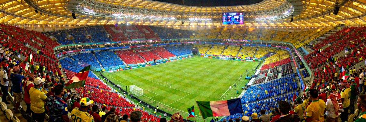 世界杯主体育场鸟瞰图，绿茵场与看台上坐满观众，气氛热烈